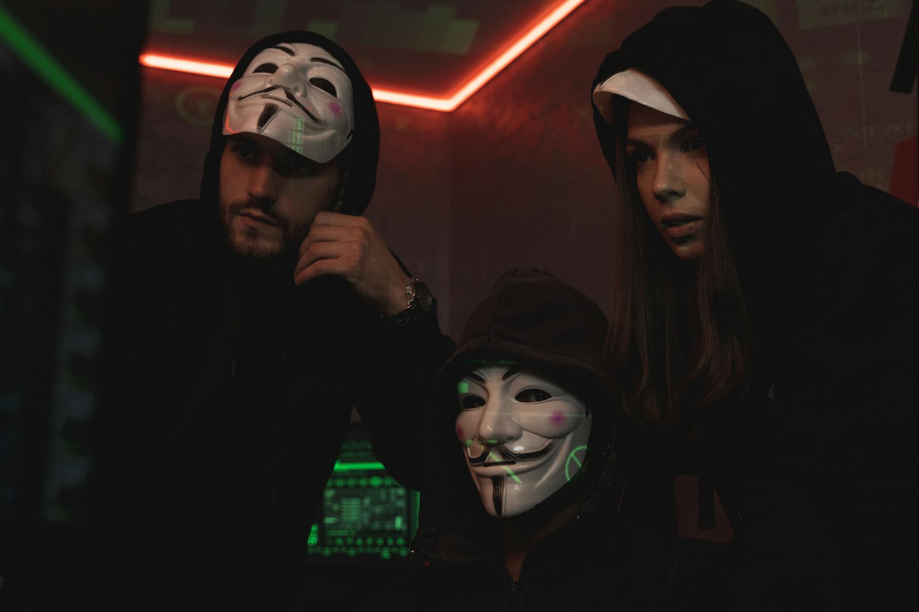 Hakerzy w maskach Guya Fawkesa w ciemnym, futurystycznym pomieszczeniu