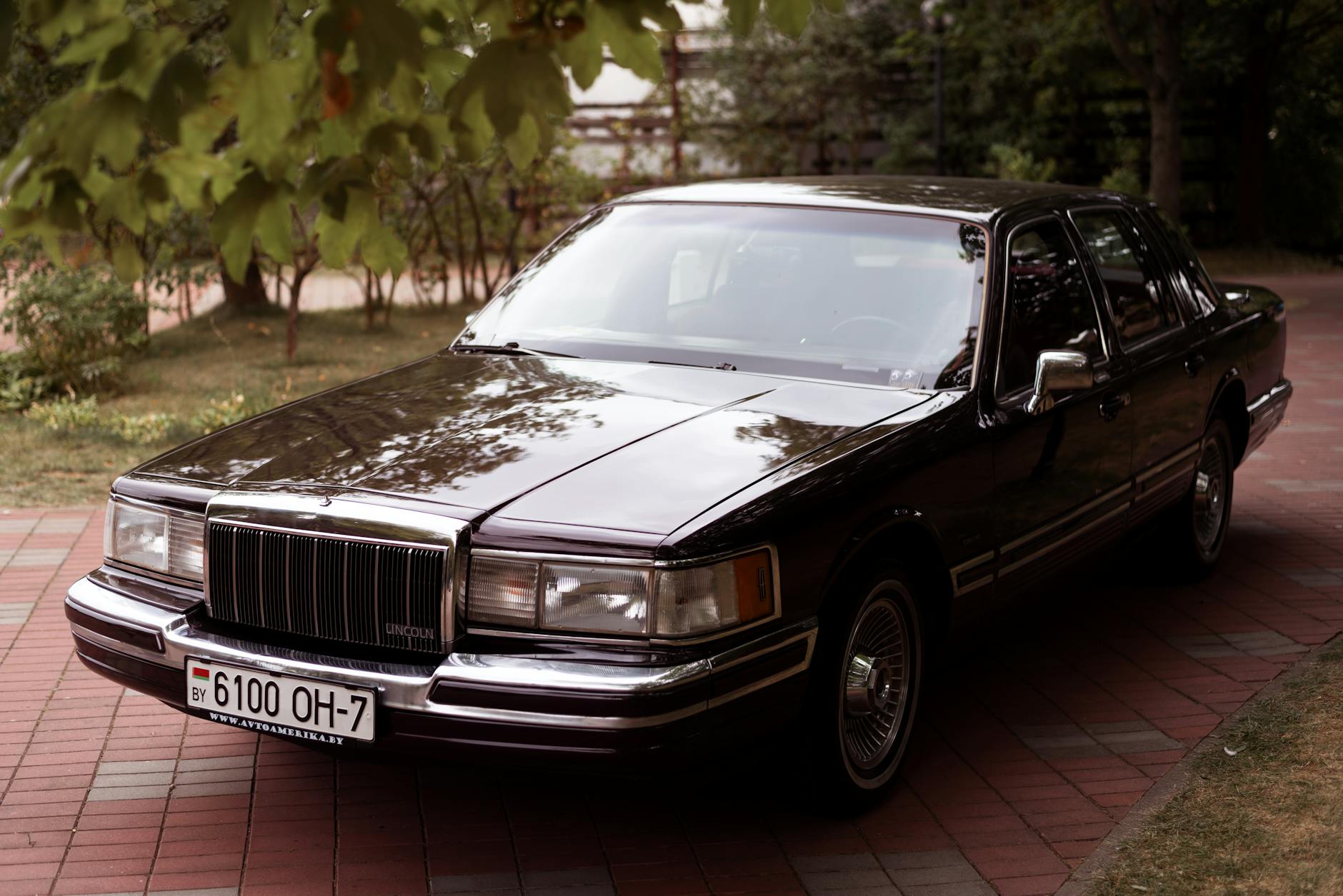Klasyczny Lincoln Town Car z 1992 roku zaparkowany w alei drzew