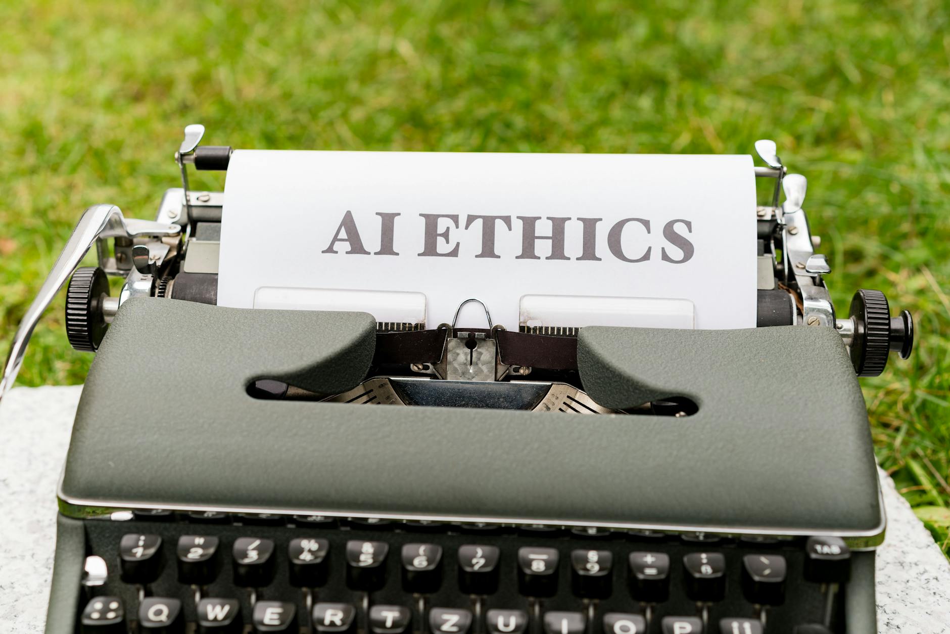Stara maszyna do pisania na dworze z kartką z napisem AI ethics