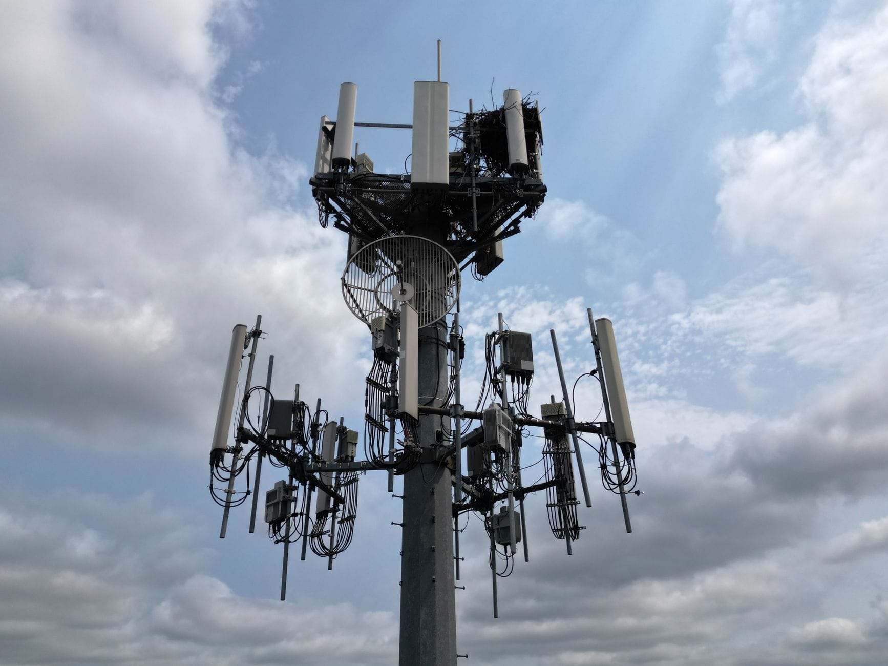 Maszt 5G z antenami na tle pochmurnego nieba