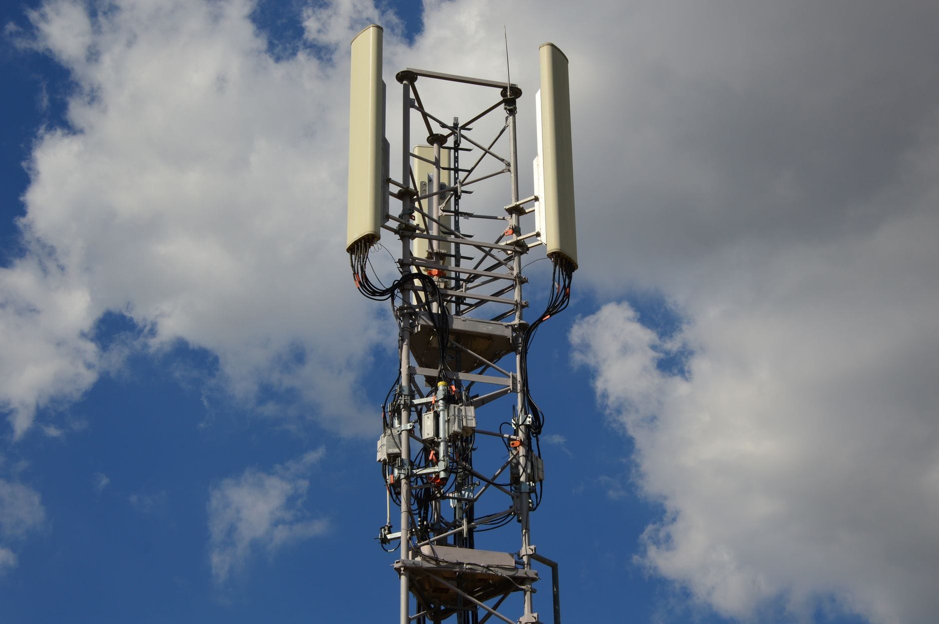 Maszt 5G z nowoczesnymi antenami na tle nieba z chmurami